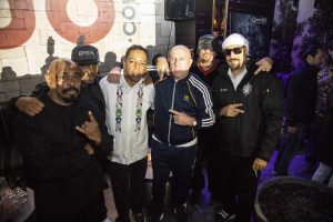 Chuck D from Public Enemy stands for a pic with Cypress Hill, as the 2018 bud logo looms over their right shoulders, and the bud.com founders stand off to their left